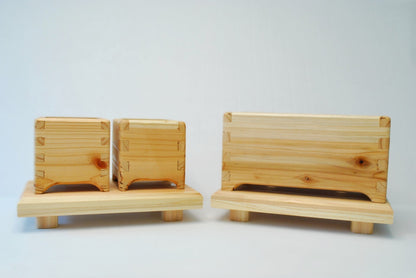 Handmade rectangular cedar display stand with minimalist design, featuring a smooth natural wood surface and short cylindrical legs, ideal for showcasing plants, candles, or decor.