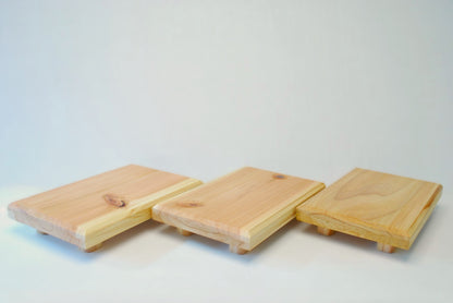 Handmade rectangular cedar display stand with minimalist design, featuring a smooth natural wood surface and short cylindrical legs, ideal for showcasing plants, candles, or decor.