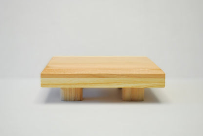 Handmade square cedar display stand with minimalist design, featuring a smooth natural wood surface and short cylindrical legs, ideal for showcasing plants, candles, or decor.